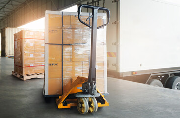 Stacked of Package Boxes on pallet with Hand Pallet Truck. Trailer Truck Parked Loading at Dock...