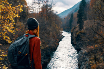 Fototapeta na wymiar woman tourist with backpack admires nature river mountains travel
