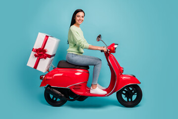 Fototapeta na wymiar Profile side view of attractive cheerful girl riding moped delivering giftbox holiday isolated over bright blue color background
