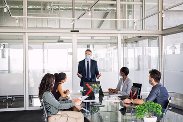 Business people in meeting wearing face masks in corporate office