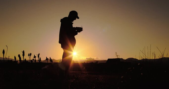 Sagoma di un ragazzo mentre pilota il drone al tramonto