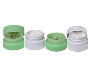 Cosmetic products. Close-up of four opened green and white plastic jars with face cream isolated on a white background. Advertising spa, make-up and beauty. Macro.
