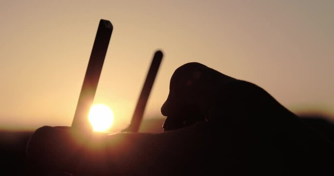 Sagoma di un ragazzo mentre pilota il drone al tramonto
