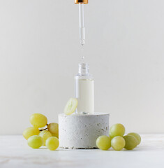 Female hand dripping natural grape seed oil into glass bottle