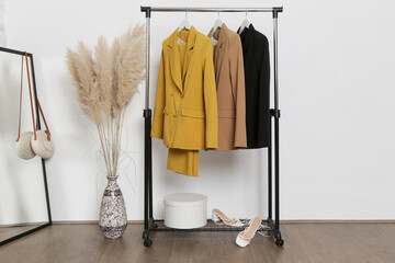 Corner in fashion atelier with fashionable tailored blazers hanging on a rack. Modern premium quality hand made woman's fashion.