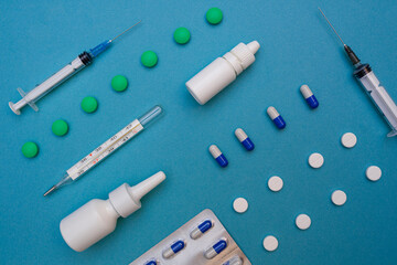 Medical equipment, pills, thermometer, syringes, drops on a blue background. The concept of treating flu and colds, various viruses. Top view with copy space. Health care and medical concept.Flat lay
