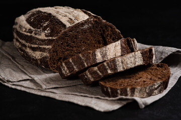 Artisan sliced rye bread. Closeup of slices of freshly baked sourdough bread on dark background....