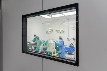 Selective focus team of doctor doing operation using medical equipment. Group of surgeons in operating room with surgery equipment. Medical background. View from the window to the operating room.