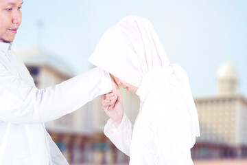 Young woman kissing her husband hands at Eid