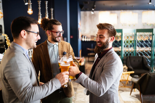 Business people drink beer after work in pub. Businessmen enjoy a beer.