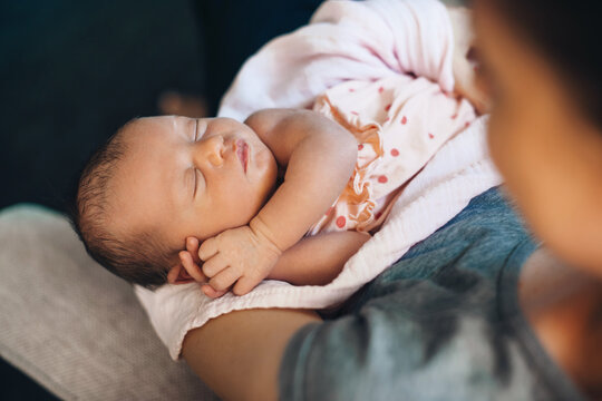 Upper view photo of a caucasian mother holding her newborn kid on hands napping