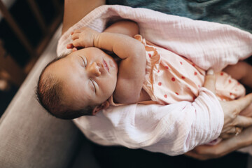 Caucasian mother holding her sleeping newborn baby at home admiring her