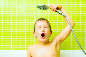 Funny expression of a boy portrayed when taking a shower and pouring water down his face to clean his hair, yellow background. - obrazy, fototapety, plakaty