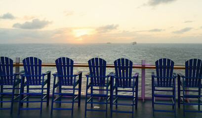 Fototapeta na wymiar Wooden deck chairs on cruise ship in a beautiful sunset time