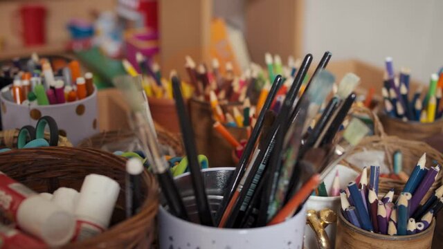 Pencils, crayons and other stationery in cups. SLow panning shot