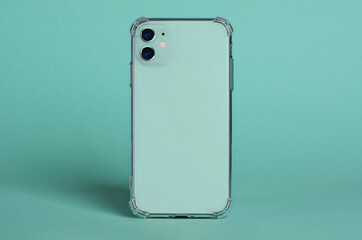 Green smartphone in clear silicone case back view. iPhone 11 case mockup isolated on green...