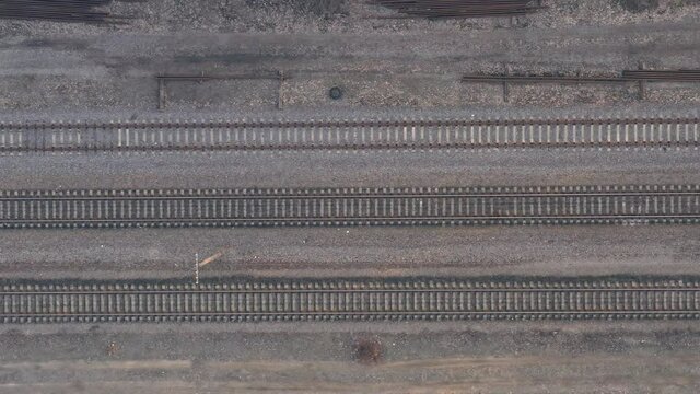 Railroad rails and sleepers - Top View Drone Panorama. Smooth Flight over empty railway tracks. Drone Flying Over Railway Tracks