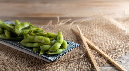 Edamame green soy beans in a bowl. Japanese appetizer Edamame green soy beans seasoned with salt in a bowl, with shop sticks on the side.