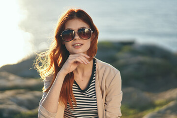 happy woman in glasses travels on nature in the mountains near the sea and striped t-shirt sweater model