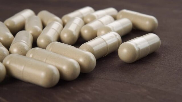 Alternative medicine herbal medical capsules close up. Dark wooden background. Macro. Dolly Shot