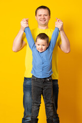 Portrait of emotional dad and his son on yellow background