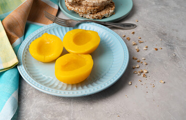 Sliced canned yellow peach with syrup on a blue plate