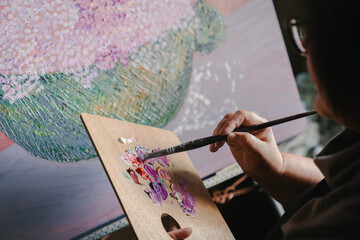 Woman concentrated to creative painting process. Painting art, home studio, painting tools, color blending.