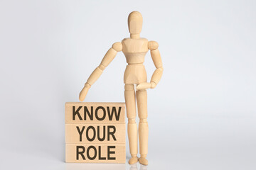 Wooden man shows with a hand text KNOW YOUR ROLE concept on the wooden block