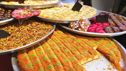Assorted different types of baklava on large trays in the market. Oriental sweets are sold in the bazaar. Traditional delicacy of the peoples of the East, mix. Grocery background