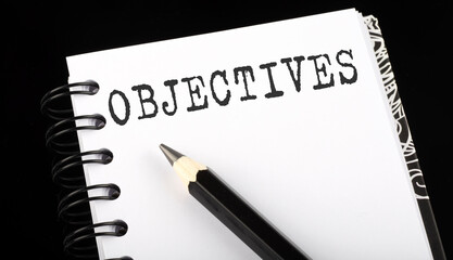 OBJECTIVES written text in small notebook on a black background