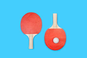 Raquetas de ping-pong con una pelota sobre un fondo celeste turquesa liso y aislado. Vista superior. Copy space. Concepto: Deportes - obrazy, fototapety, plakaty