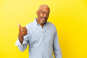 Cuban Senior isolated on yellow background pointing to the side to present a product