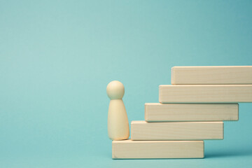 a wooden figurine of a man stands on a staircase made of blocks on the first step