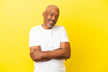 Cuban Senior isolated on yellow background with arms crossed and looking forward