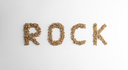 Top view on lettering ROCK made from golden nuggets on white background