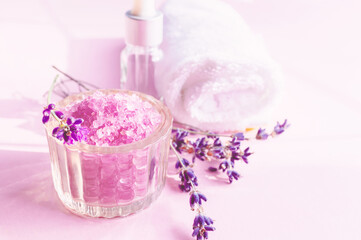 Lavender salt with natural spa products and bath decor on a pink background