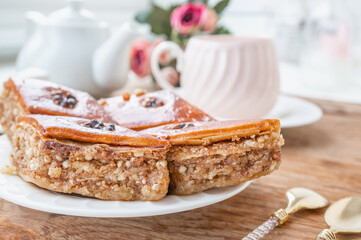 Close-up of baklava. Turkish Ramadan Arabic sweet dessert on a decorative plate, with a coffee cup in the background. Middle Eastern food baklava with nuts and honey syrup