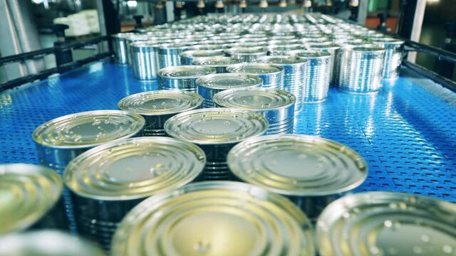 Factory conveyor is transporting newly-sealed tin cans. Factory conveyor, industrial production line with metal cans.