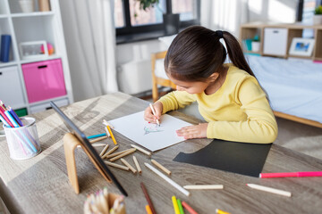 childhood, creativity and art concept - close up of little girl with coloring pencils drawing witch on paper at home