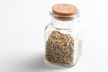 Glass jar with pieces of gold on white background
