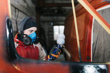 man paints a car, treatment of the body with epoxy primer.