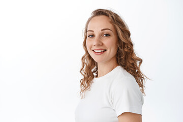 Fototapeta premium Portrait of attractive blond woman with curly hairdo, turn head at camera and smile happy, looking carefree, standing over white background