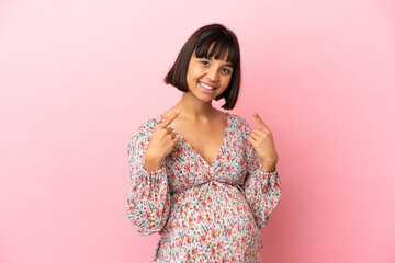 Obraz premium Young pregnant woman over isolated pink background giving a thumbs up gesture