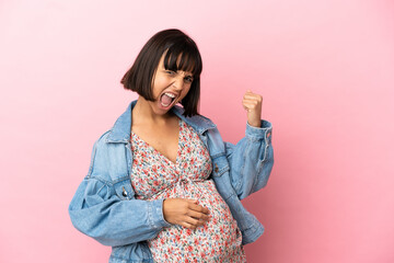 Obraz premium Young pregnant woman over isolated pink background celebrating a victory