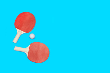 Raquetas de ping-pong con una pelota sobre un fondo celeste turquesa liso y aislado. Vista superior. Copy space. Concepto: Deportes