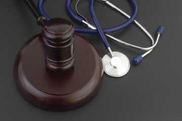 Judge gavel and stethoscope on black table. Malpractice and law in medicine concept.