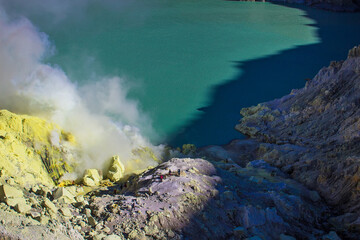 Fototapeta na wymiar Smoke of sulfur toxic gas in the acidic crater lake of Kawah Ijen volcano, Banyuwangi, East Java, Indonesia. Mount Ijen is the famous tourist attraction, where sulfur is mined.