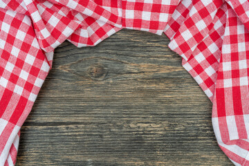 Red checkered towel on the kitchen table. Wooden table background.