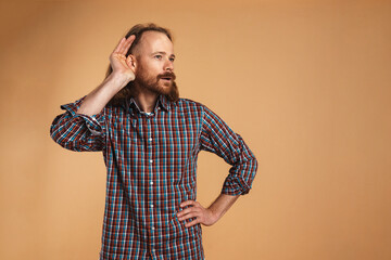 Bearded ginger focused man gesturing and eavesdropping