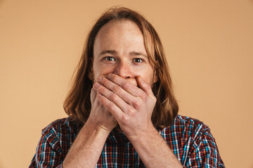 White ginger man covering his mouth and looking at camera